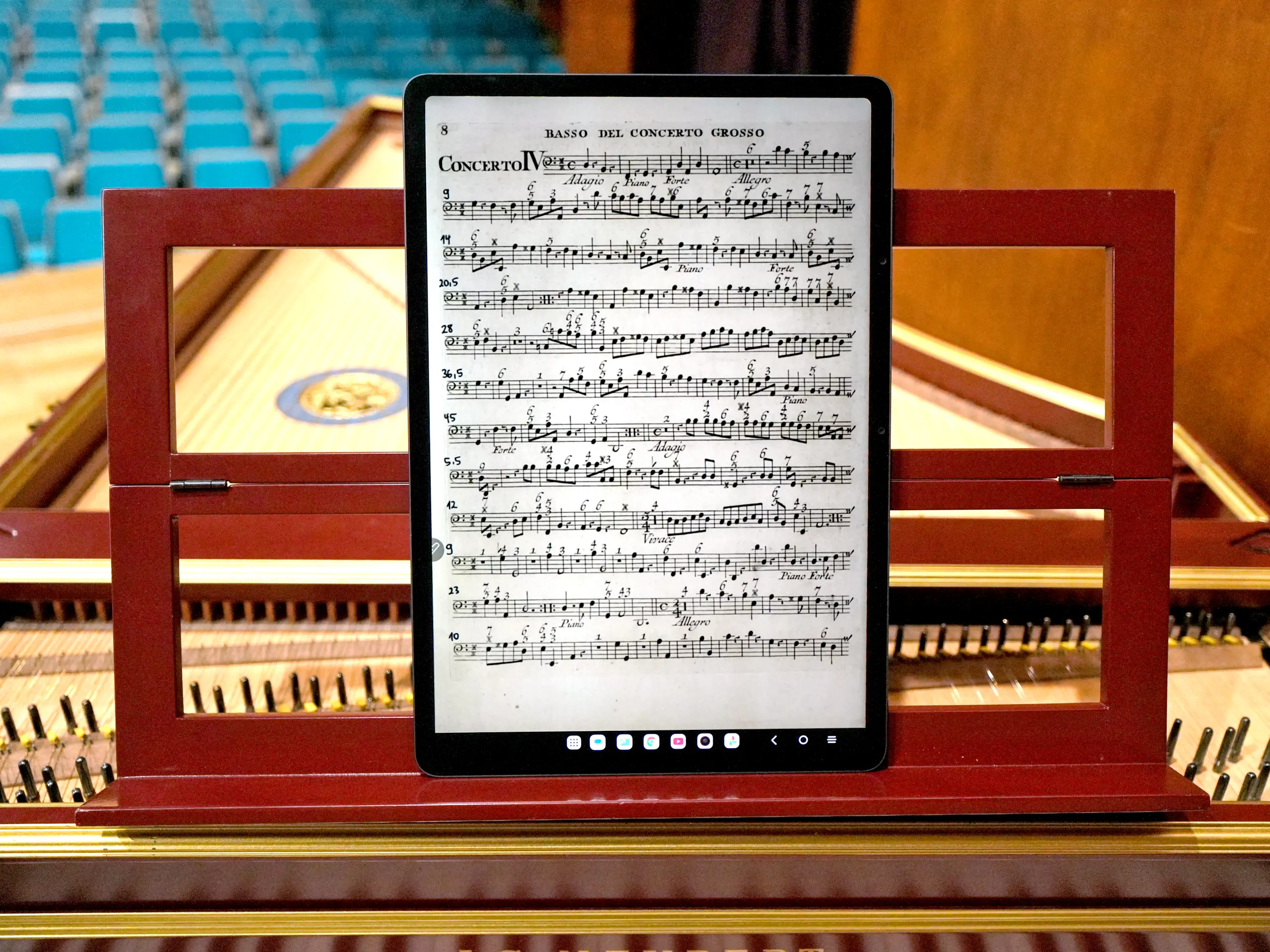 TCL NxtPaper 14 tablet displaying sheet music on a harpsichord in a concert hall